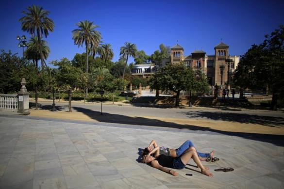 Du khách nằm phơi nắng trước bảo tàng kiến trúc ở Andalusian, Seville.