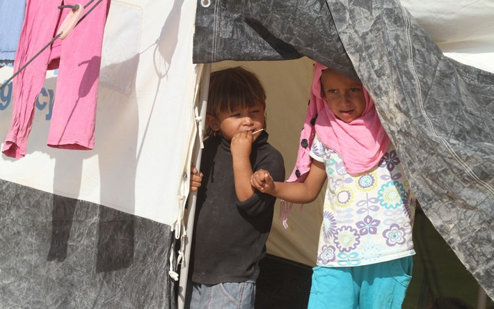 Hai chị em gái đứng trong lều tại trại tị nạn Zaatari.