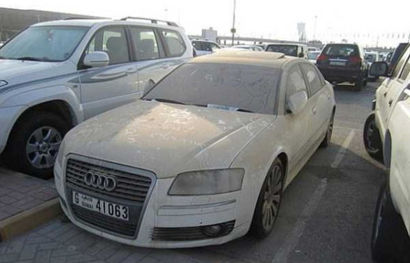 Một chiếc Audi bụi bặm nằm trơ trọi giữa bãi đỗ xe.