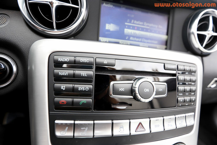 Phần trụ đỡ hai ghế có tấm kính phía sau để ngăn gió lùa khi SLK biến thành mui trần. Mercedes tỉ mỉ tới mức trang bị cả bộ sưởi phần cổ hành khách nếu mở mui trong trời lạnh. Dàn âm thanh 6 đĩa đi cùng bộ loa Harman Kardon Logic 7.