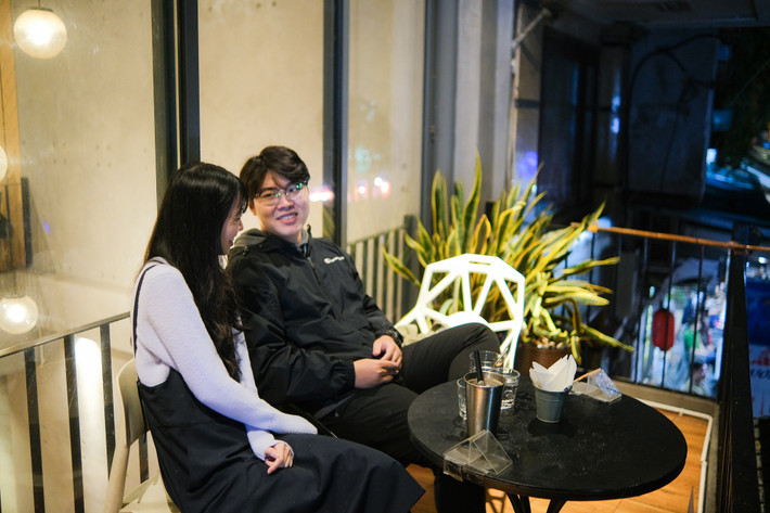 Minh Ngọc (22 tuổi) và Việt Hiếu (23 tuổi) cho biết cũng khá lâu cả hai mới đi cà phê cùng nhau buổi đêm. "Đi cà phê vào khoảng thời gian này trong ngày, mình thấy không gian yên tĩnh, riêng tư hơn. Thời tiết Hà Nội đang khá lạnh, thích hợp đi chơi nên bọn mình không quá ngại mưa gió. Ngồi tại quán cũng vui hơn so với thời điểm mấy tuần trước chỉ được mua đồ uống mang đi", Ngọc nói. Để phòng dịch, cả hai chủ động chọn chỗ ngoài trời, cách xa mọi người.