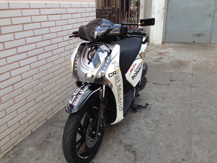 Chiếc xe độ mới toanh của fan cuồng này là sự kết hợp hài hòa giữa 2 gam màu tương phản đen trắng cùng dàn tem Real Madrid. Logo của câu lạc bộ nổi bật trên mặt nạ và dè trước của xe.