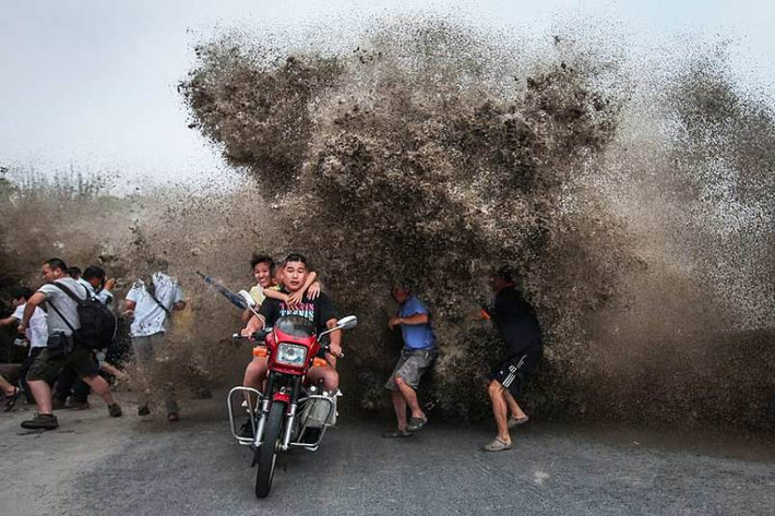 Hình ảnh một gia đình trên xe máy chạy tránh sóng thủy triều trông rất ngoạn mục.