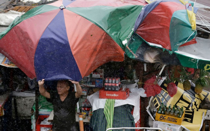 Người đàn ông giữ ô trước gió bão tại thành phố Taguig.