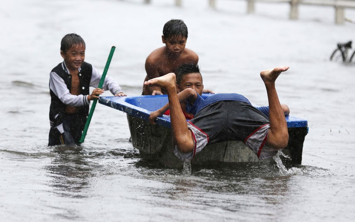 Trẻ em chơi với một bồn tắm trên đường phố ngập lụt ở ngoại ô Navotas.