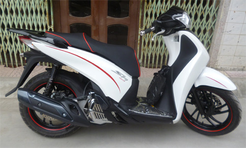 Chiếc SH 2012 màu trắng nguyên bản được chủ nhân của nó độ kiểu dáng thể thao khi sơn lại vành xe, giảm xóc, tay nắm phía sau, phun carbon ở phần đầu xe hay yên xe với đường chỉ đỏ.