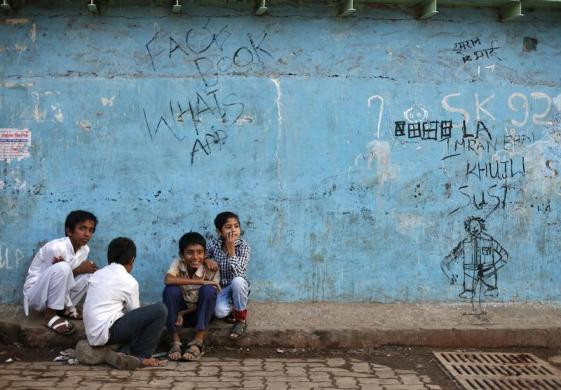 Những cậu bé ngồi bên cạnh một bức tường ở Dharavi thuộc thành phố Mumbai - một trong những khu ổ chuột lớn nhất châu Á vào tháng 1/2014.