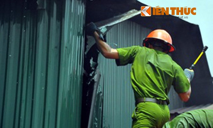 Chiến sĩ công an liên tục phá các tấm tôn bao quanh kho cồn để chữa cháy.