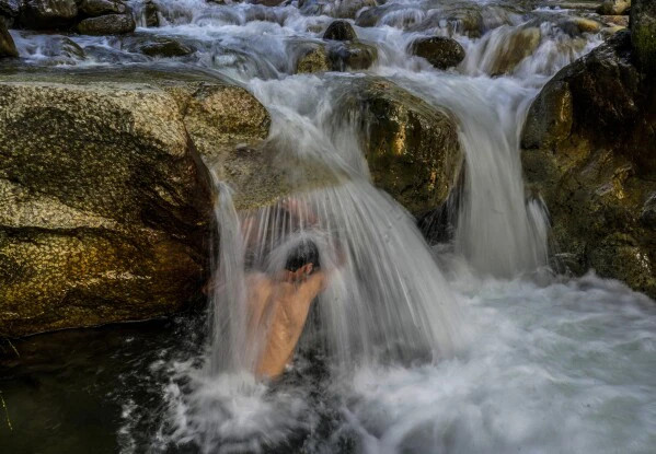 Người đàn ông Kashmir tránh nóng bên dòng suối ở ngoại ô Srinagar, Kashmir