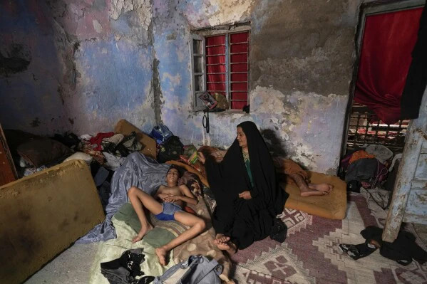 Một phụ nữ Iraq quạt cho con mình trong lúc mất điện tại nhà của họ ở Baghdad, Iraq