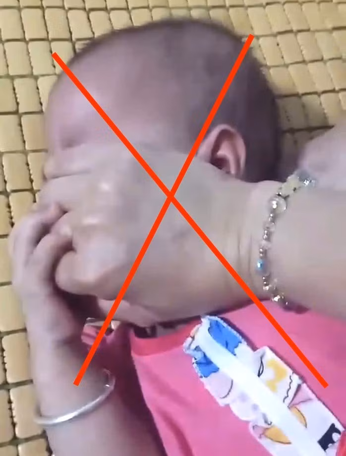 Mẹ dùng tay bịt miệng, mũi con gái mới 8 tháng tuổi gây phẫn nộ cộng đồng mạng. Ảnh cắt từ clip/Nguồn NLĐ