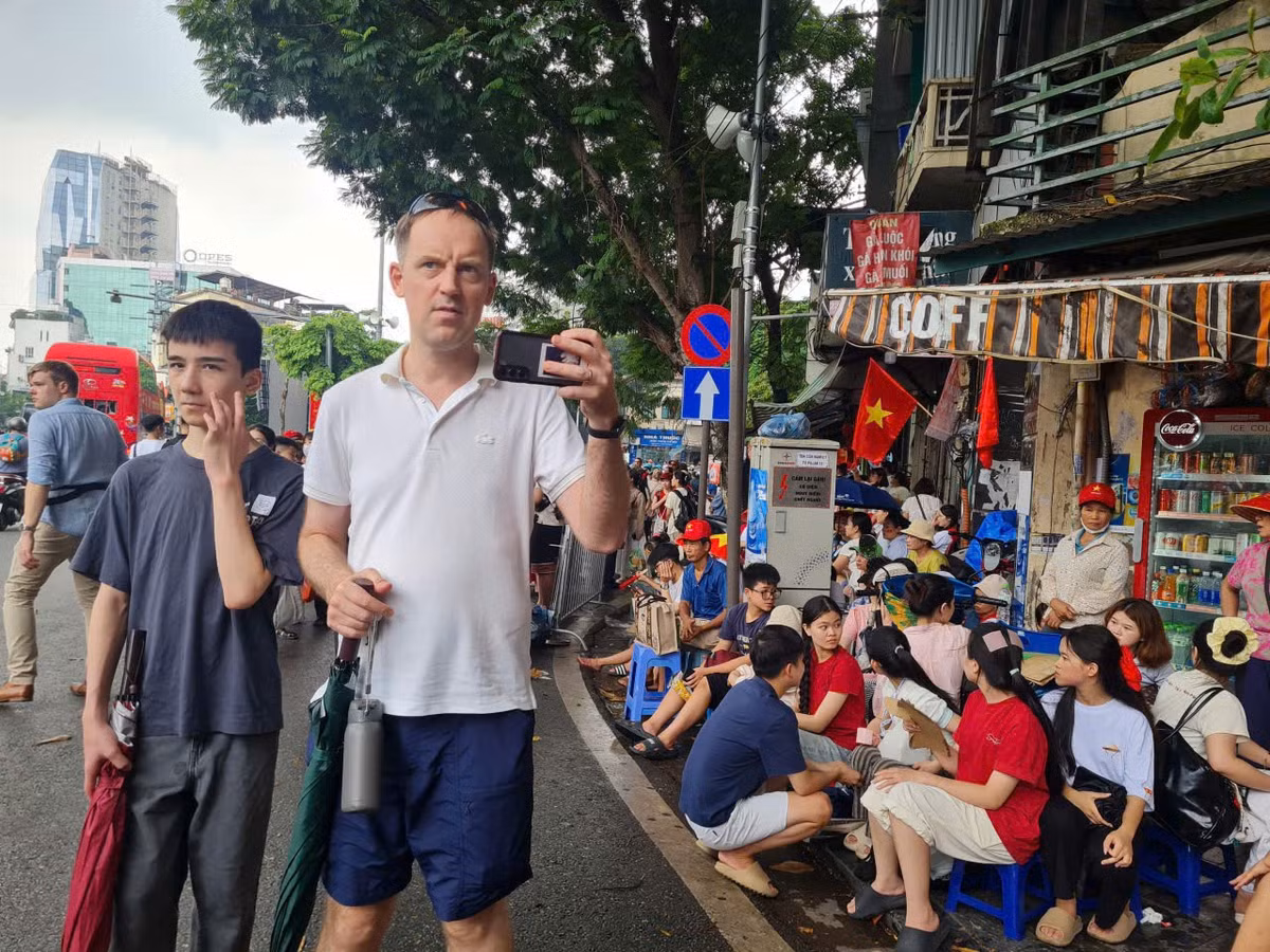 Một du khách nước ngoài đưa máy quay ghi lại hình ảnh hai bên phố.