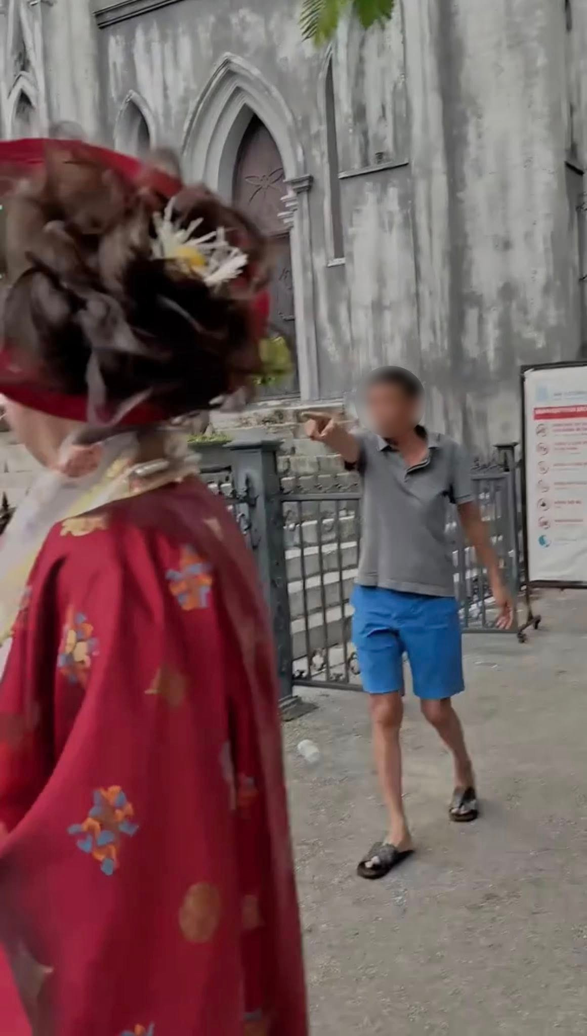 Ngân 98 bị yêu cầu rời đi do &quot;chiếc mấn đội đầu vi phạm quy định &apos;không đội mũ&apos; được ghi trên bảng thông báo đặt trước cổng nhà thờ&quot;. Ảnh cắt từ video.