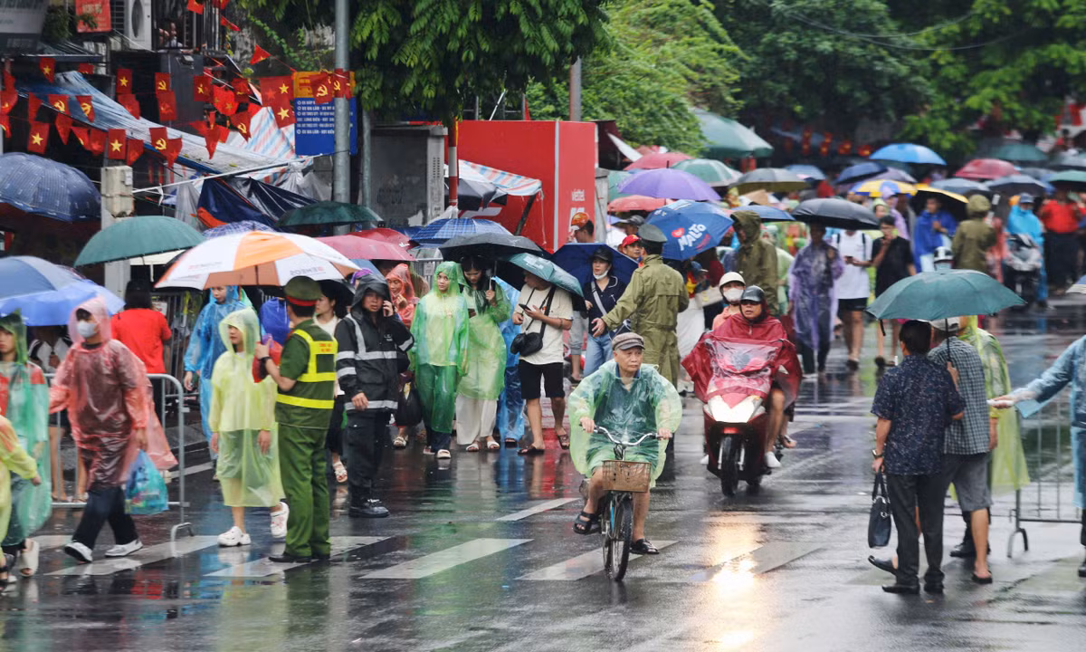 Nhiều người mặc áo mưa, cầm ô di chuyển cố tìm cho mình một chỗ ngồi để đợi xem diễu binh A80.