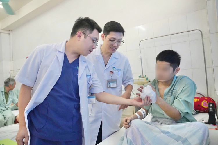 ThS.BSNT Lâm Thanh Hải và BS Cao Đức Mạnh thăm khám bàn tay cho bệnh nhân sau phẫu thuật - Ảnh BVCC dut-roi.jpg