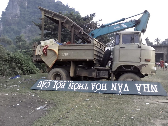 Biển "Nhà Văn Hóa Thôn Bôi Câu" bị người dân trong thôn dỡ hẳn xuống, đặt cạnh ô tô tải và máy cẩu mà một số cá nhân đã sử dụng để khai thác vàng trái phép trên bãi Giữa con sông Bôi.