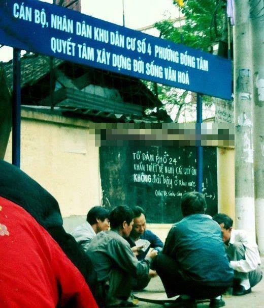 Nhóm nam giới tụ tập chơi bài ngay bên dưới tấm biển kêu gọi, vận động người dân sống trong khu vực "quyết tâm xây dựng đời sống văn hóa". Ảnh: FB.