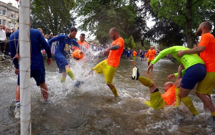 Người dân tham gia trận bóng đá trên nước thường niên ở River Windrush tại Bourton-on-the-Water, Gloucestershire, Anh, ngày 28/8. Ảnh: Reuters.