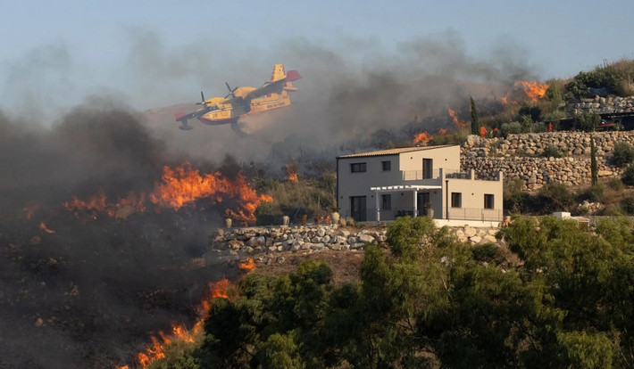 Máy bay Canadair bay qua khu vực cháy rừng ở Trapani, Sicily, Italy, ngày 27/8. Ảnh: Reuters.