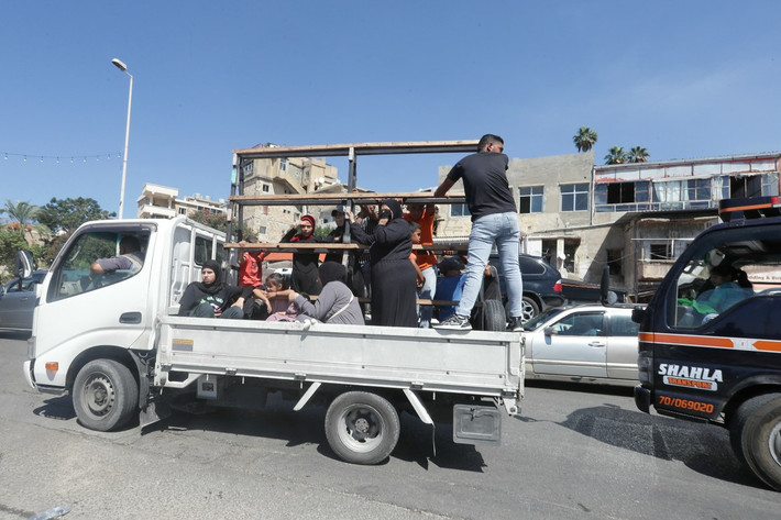 Các thành viên của một gia đình người Syria mang theo đồ đạc phía sau xe tải ở Sidon.