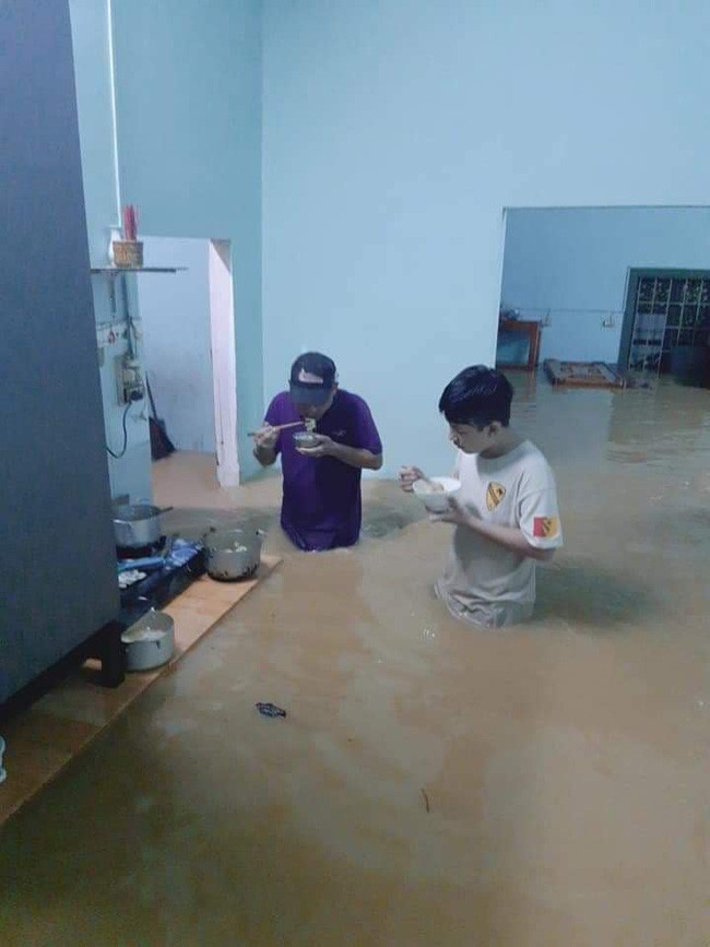 Hình ảnh hai bố con ăn cơm trong nước lũ ngập nửa người...