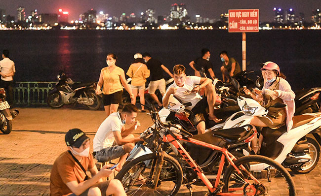 Rất nhiều các bạn trẻ vô tư bỏ đeo khẩu trang, tụ tập tại vỉa hè đường Thanh Niên (phía ven Hồ Tây).