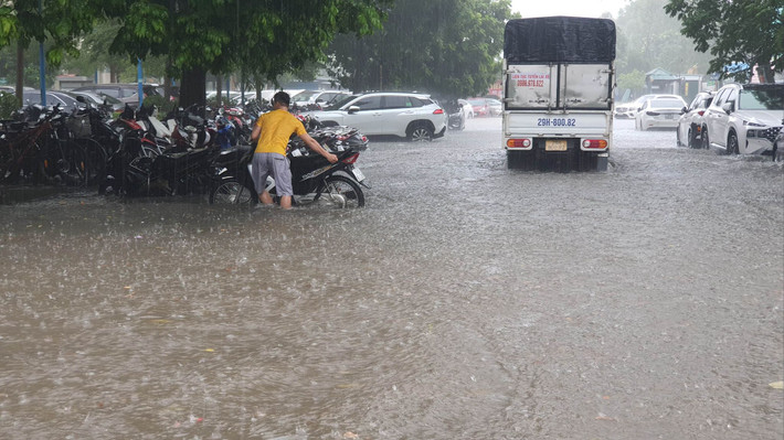 Do mưa lớn đường bị ngập nên bảo vệ phải dắt xe máy lên cao.