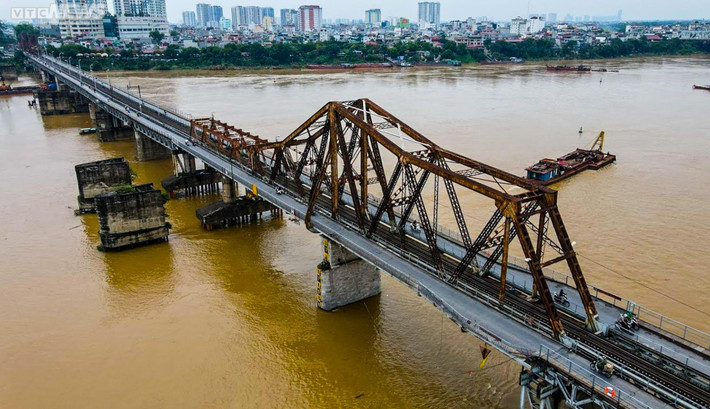Cầu Long Biên (tên cũ là cầu Paul Doumer) là cây cầu bắc qua sông Hồng kết nối quận Hoàn Kiếm, quận Ba Đình với quận Long Biên của Hà Nội. Cầu được xây dựng từ năm 1898 tới năm 1902 bởi công ty Daydé & Pillé, được sử dụng vào năm 1903. Cầu dài 2290m qua sông và 896m cầu dẫn, gồm 19 nhịp dầm thép đặt trên 20 trụ cao hơn 40m (kể cả móng) và đường dẫn xây bằng đá. Cầu dành cho đường sắt đơn chạy ở giữa. Hai bên là đường dành cho xe cơ giới và đường đi bộ. Đường cho các loại xe là 2,6m và luồng đi bộ là 0,4m. Cầu Long Biên là chứng nhân lịch sử của Hà Nội, tượng trưng cho sự hiên ngang, dũng cảm của Thủ đô trong thời kỳ chống thực dân Pháp và đế quốc Mỹ. (Ảnh VTC News)