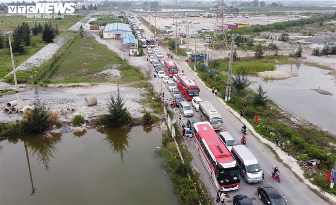 Tuy nhiên, do lượng phương tiện khá đông nên hầu hết xe ô tô chở khách du lịch phải đợi cả tiếng đồng hồ. Nhiều du khách phải xuống đi bộ vào chờ ở khu vực gần bến phà. (Ảnh: VTC News)