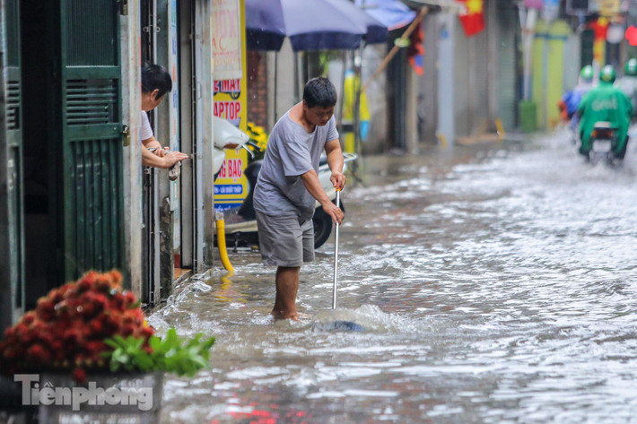 Người đàn ông đang cố quét nước ra ngoài không cho tràn vào nhà.
