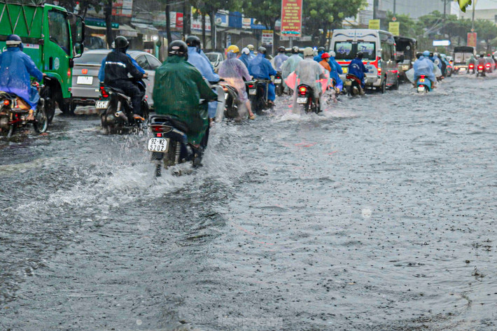 Dòng người vội vã đi làm dưới trời mưa lớn, xe cộ ùn tắc do nước ngập.