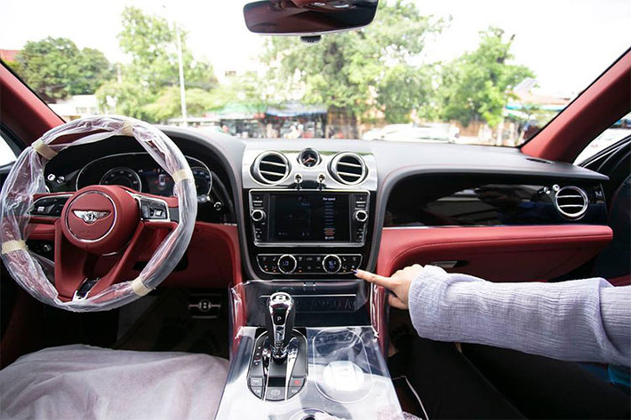Đối lập bộ áo màu đen, bên trong khoang lái chiếc Bentley Bentayga V8 đầu tiên cập bến Campuchia có nội thất bọc da cao cấp màu đỏ đun hết sức ấn tượng, một số chi tiết khác của xe cũng được ốp bằng gỗ quý.
