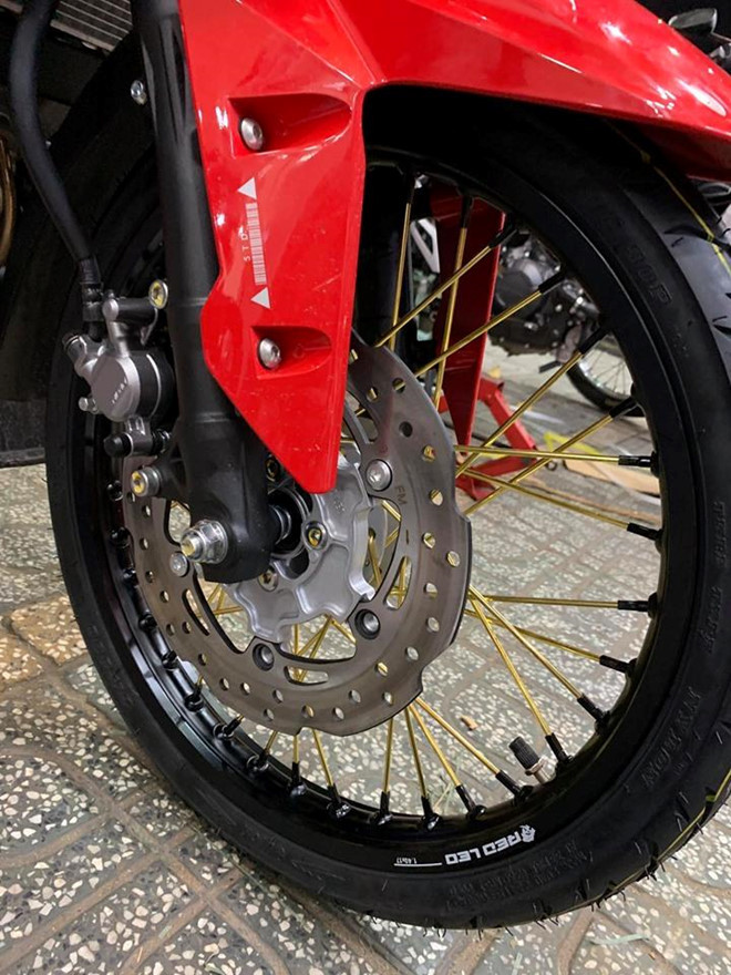 Dàn chân nguyên bản trên côn tay Honda Winner X được thay thế bằng cặp vành nhôm đến từ thương hiệu Red Leo kết hợp cùng bộ căm vàng nổi bật. Bánh căm mới này có kích thước 1.4 ở phía trước và 1.6 ở phía sau, cặp lốp nguyên bản cũng đã được chủ nhân thay bằng lốp đến từ hãng Quick và Maxis. Sử dụng bánh căm giúp cho xe vượt qua các địa hình êm ái hơn, ngoài ra khối lượng xe cũng được giảm đáng kể.