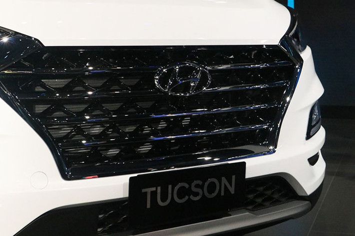 Tucson 2019 là bản nâng cấp giữa vòng đời, xe được thiết kế theo phong cách “Cascading” đặc trưng của Hyundai. Tấm lưới tản nhiệt ở phiên bản lần này cứng cáp hơn với 4 thanh ngang mạ chrome xếp song song, cùng cặp đèn pha LED được mở rộng từ hai góc trên. Bên dưới, bộ đèn sương mù được thu nhỏ, bao quanh bởi dải đèn LED hình chữ L.