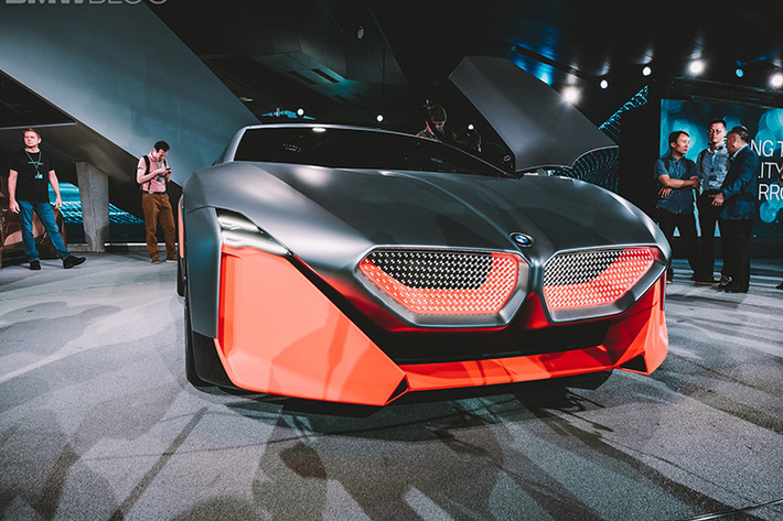 Thậm chí là nhìn từ một số góc độ, Vision M Next còn có một dáng vẻ rất chất “Lamborghini Gallardo.” Phần mũi xe nằm thấp, có trang bị đèn pha Laser Wire, cửa cánh chim, ốp ngưỡng cửa bằng sợi carbon, bộ la-zăng hợp kim với họa tiết chấu hình chữ Y và một lớp sơn vô cùng sống động, kết hợp màu cam Thrilling Orange và kim loại bạc Cast Silver.