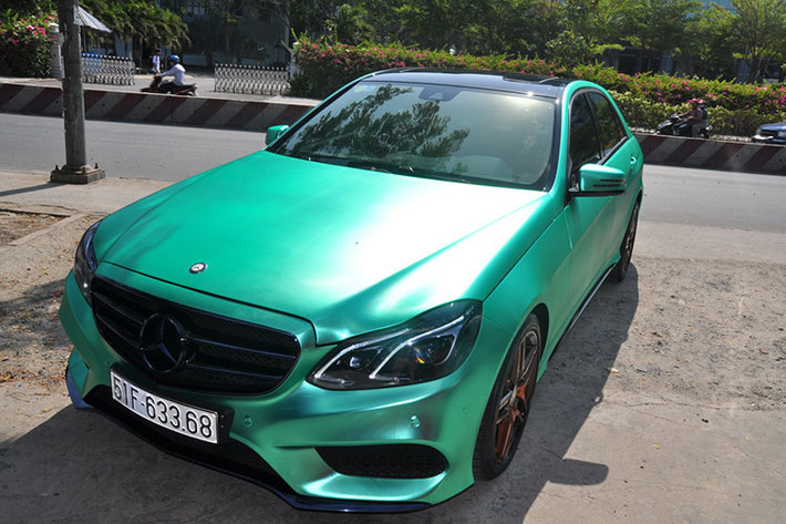 Chiếc Mercedes E250 AMG được chủ nhân “độ nhẹ” với lớp sơn xe được dán phủ bằng đề-can crôm màu xanh độc đáo biến màu theo từng góc độ nhìn. Nếu chỉ nhìn lướt qua, bạn sẽ khó có thể nhận ra đây là chiếc xe được dán đề can.