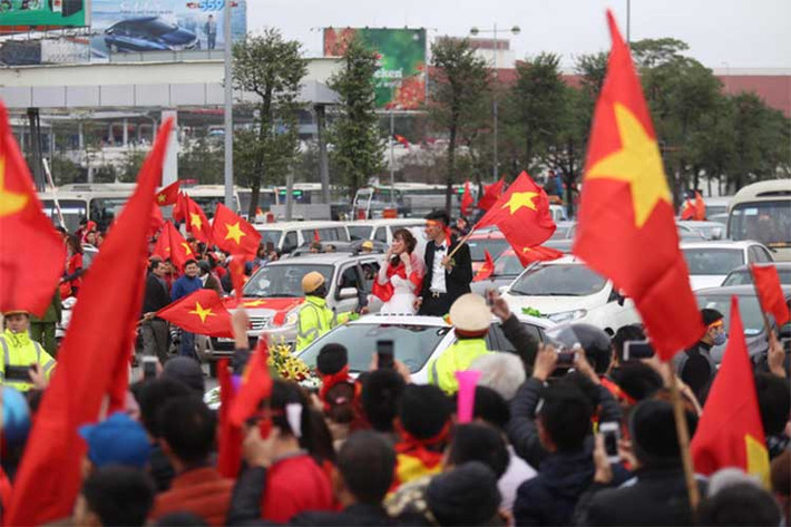 Tuy nhiên không cảm thấy phiền lòng, cả cô dâu và chú rẻ liền diện băng rôn, choàng Quốc kỳ và vẫy cờ hoà cùng bầu không khí xung quanh.