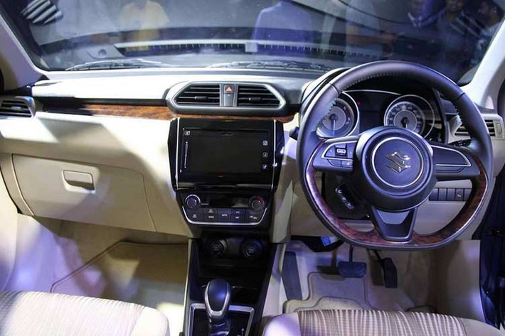 Bên cạnh đó, bảng táp-lô của xe cũng được thiết kế với các đường kẻ ngang và hệ thống giải trí thông tin nổi. Vô-lăng 3 chấu được kế thừa từ mẫu Swift mới, hai ghế trước được thiết kế với hai tông màu be và màu nâu. Ngoài ra, các trang bị nổi bật khác có thể kể đến như cổng sạc 12V cho ghế trước/sau, đầu cắm USB và audio, 4 loa và cảm biến lùi.