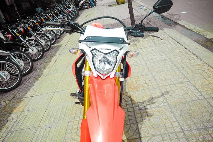 Cụ thể, ở phần đầu hãng xe máy Honda đã thiết kế cho CRF150 với đèn pha hình kiên kèm các đèn xi-nhan hai bên cùng ốp bảo vệ kiêm cả gió. Tuy nhiên các đèn này vẫn sử dụng bóng sợi đốt halogen thay vì đèn LED như nhiều mẫu xe mới đang bán ra thị trường hiện nay.