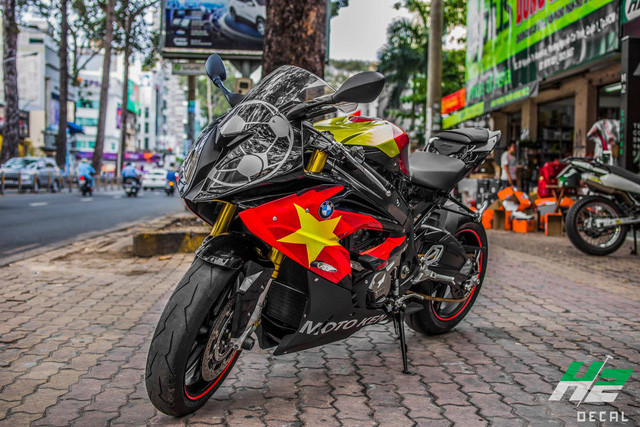 Chiếc siêu môtô BMW S1000RR trong bài viết này đã được chủ nhân khoác lên mình bộ áo mới lấy cảm hứng từ Quốc Kì cờ đỏ sao vàng của Việt Nam. Bình xăng, yếm 2 bên thân xe đều được dán decal cờ đỏ sao vàng nổi bật trên nền màu đen.