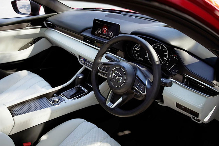 Bên trong Mazda6 2018 xuất hiện mặt táp-lô được kéo dài theo chiều ngang hoàn toàn mới. Chỉ có vô lăng và một số chi tiết ốp trang trí là được đưa từ phiên bản cũ sang. Nội thất theo phong cách tối giản của Mazda6 2018 đi kèm hệ thống điều hòa mới, cửa gió điều hòa thanh mảnh hơn và các chi tiết ốp gỗ trang trí Sen Nhật Bản.