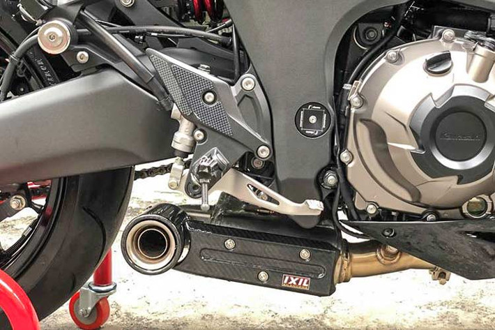 Khối động cơ nguyên bản của Z1000 vẫn được chủ nhân giữ nguyên bản, chỉ độ lại hệ thống xả Ixil full carbon, đồng thời được bảo vệ thêm bằng những chi tiết ốp bưởng máy CNC và chống đổ. Lùi về phía sau một chút là dàn để chân Rizoma và một số đồ chơi khác...