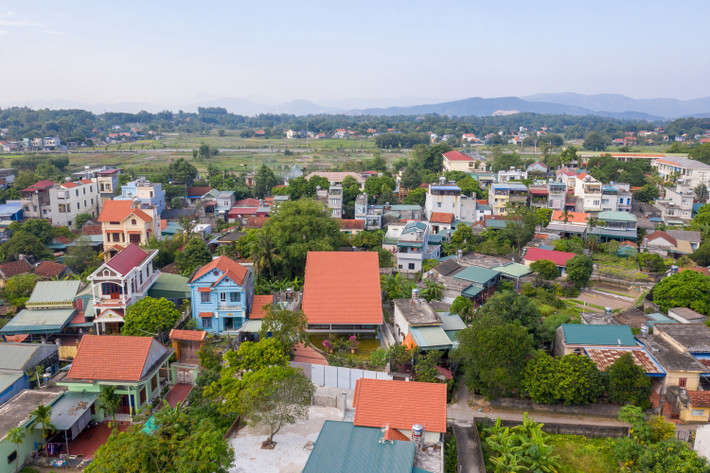 Phía trước mặt nước là vườn hoa và sân gạch đỏ dẫn vào nhà.