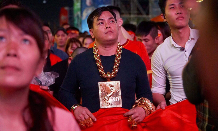 Trần Ngọc Phúc (Phúc XO) nổi tiếng khi đeo nhiều 'vàng' ra phố đi bộ Nguyễn Huệ để xem bóng đá giải AFF Cup. Lúc này anh mang nhiều trang sức khủng, thậm chí còn có 5 vệ sĩ đi theo, có người đỡ vòng cổ cho đỡ nặng. Ảnh: Internet.
