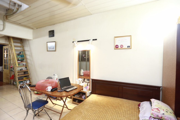 Vách gỗ đơn giản gắn với kệ để TV ngăn cách giữa phòng khách và một giường ngủ. Ảnh: Internet