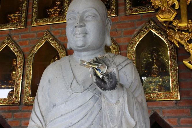 Tình trạng nhét tiền lẻ vào tượng Phật vẫn diễn ra tại chùa Bái Đính. Ảnh: Tuổi Trẻ.