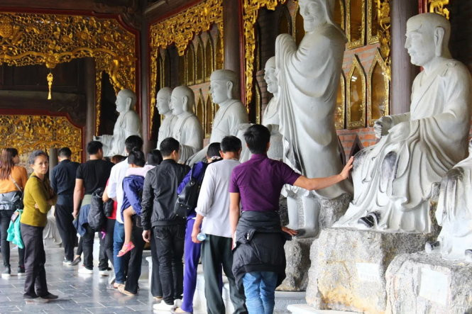 Điều đáng buồn chính là thái độ "bất chấp tất cả" của người dân khi đi lễ chùa, dù đã được nhắc nhở song nhiều người vẫn cố tình vi phạm các quy định. Hình ảnh phản cảm của người Việt được chụp tại chùa Bái Đính ngày khai hội 2/2. Bức hình cho thấy nhiều người vẫn vô tư sờ tượng thần, Phật... với quan niệm cầu may. Ảnh: Tuổi Trẻ.
