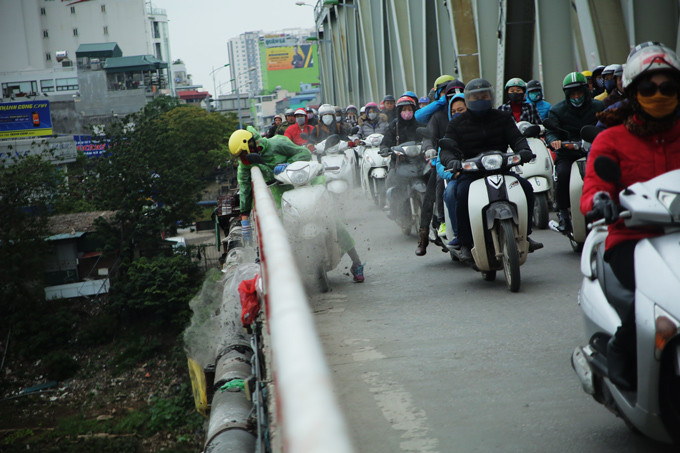 Sáng 23 tháng Chạp (20/1), nhiều người dân thả cá chép và tro trên cầu Chương Dương khiến bụi tro bay mù mịt. Không chỉ làm mất vệ sinh môi trường, hành động dừng xe bất ngờ giữa cầu của nhiều người khiến giao thông tại khu vực này bị ảnh hưởng. Ảnh: Vietnamnet.