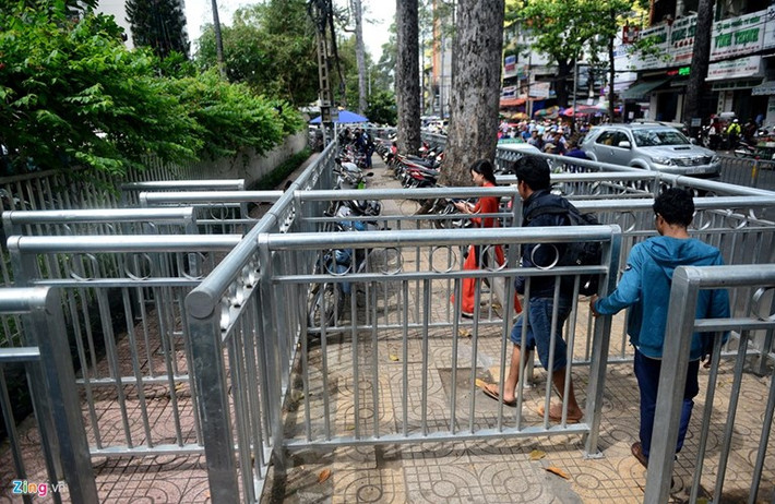 Hơn 2 tháng nay, vỉa hè trước và bên hông Bệnh viện Chợ Rẫy (phường 12, quận 5, TP HCM) được lắp dải phân cách rất kiên cố để tạo lối đi cho người đi bộ. Tuy nhiên, rào chắn không giải quyết được tình trạng lấn chiếm vỉa hè, lại bị phản tác dụng khi đẩy những người bán hàng rong xuống ngay dưới lòng đường gây khó khăn cho giao thông và người qua lại. Ảnh: Zing.