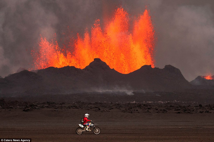 Một người mạo hiểm lái xe mô tô quanh miệng núi lửa Holuhraun khi nó đang phun trào dung nham nóng.